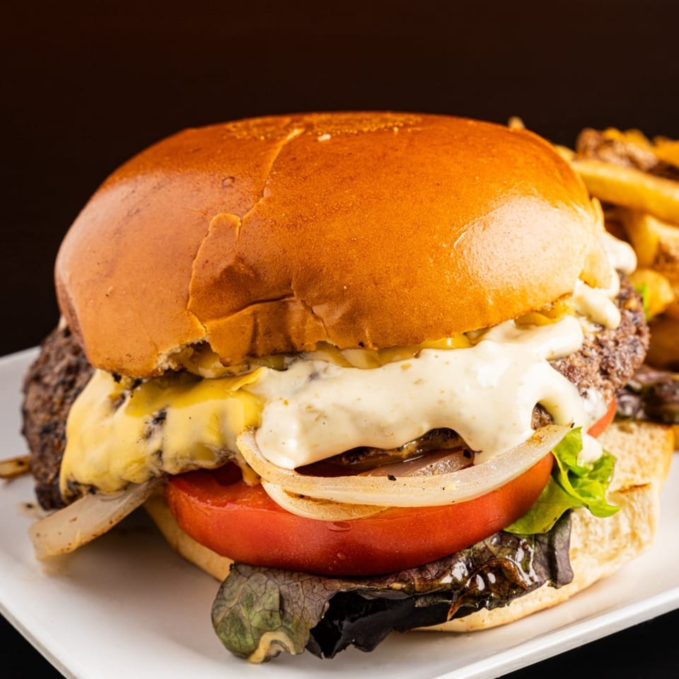 Juicy Tex-Mex burger with melted cheese, onions, tomato, and lettuce, served with fries.