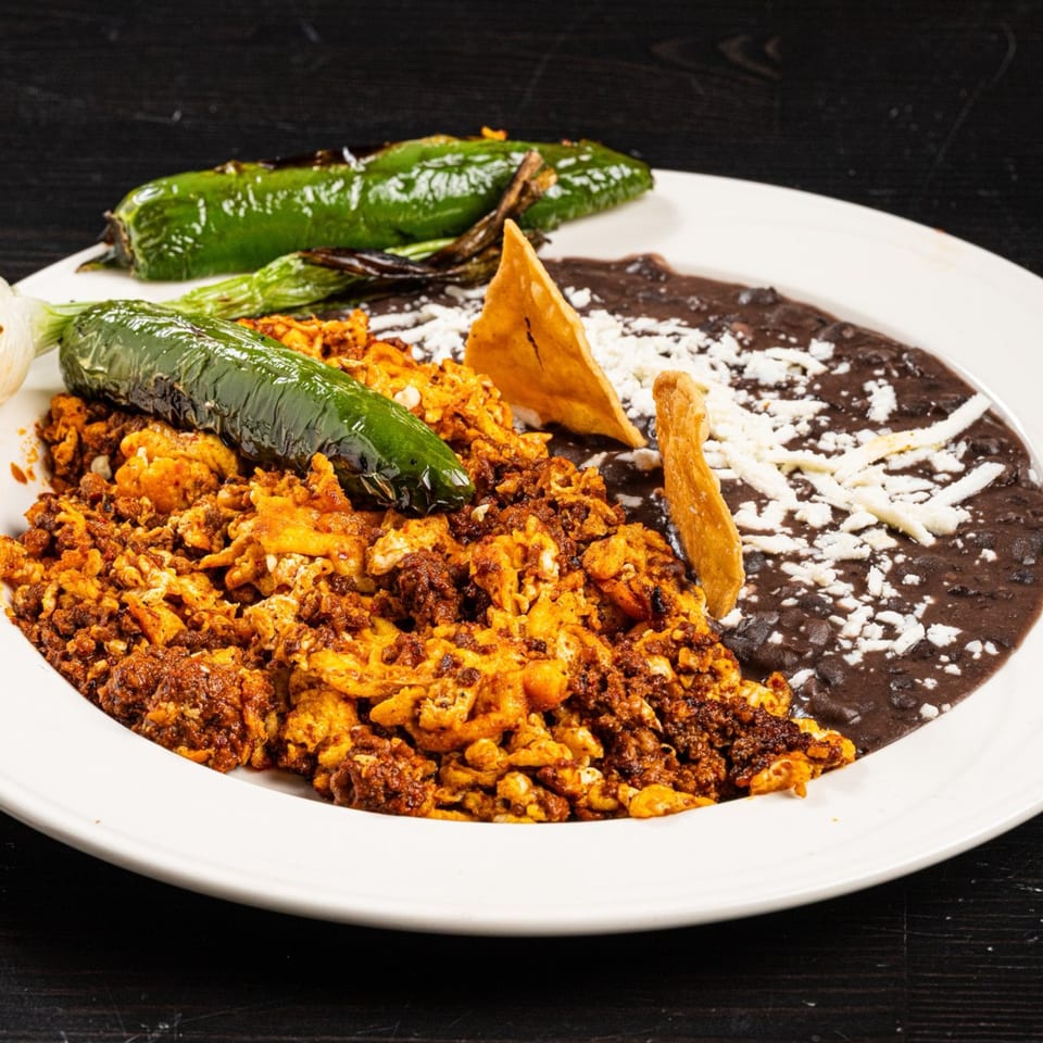 Tex-Mex breakfast plate with scrambled eggs and chorizo, black beans, grilled peppers, and tortilla chips.