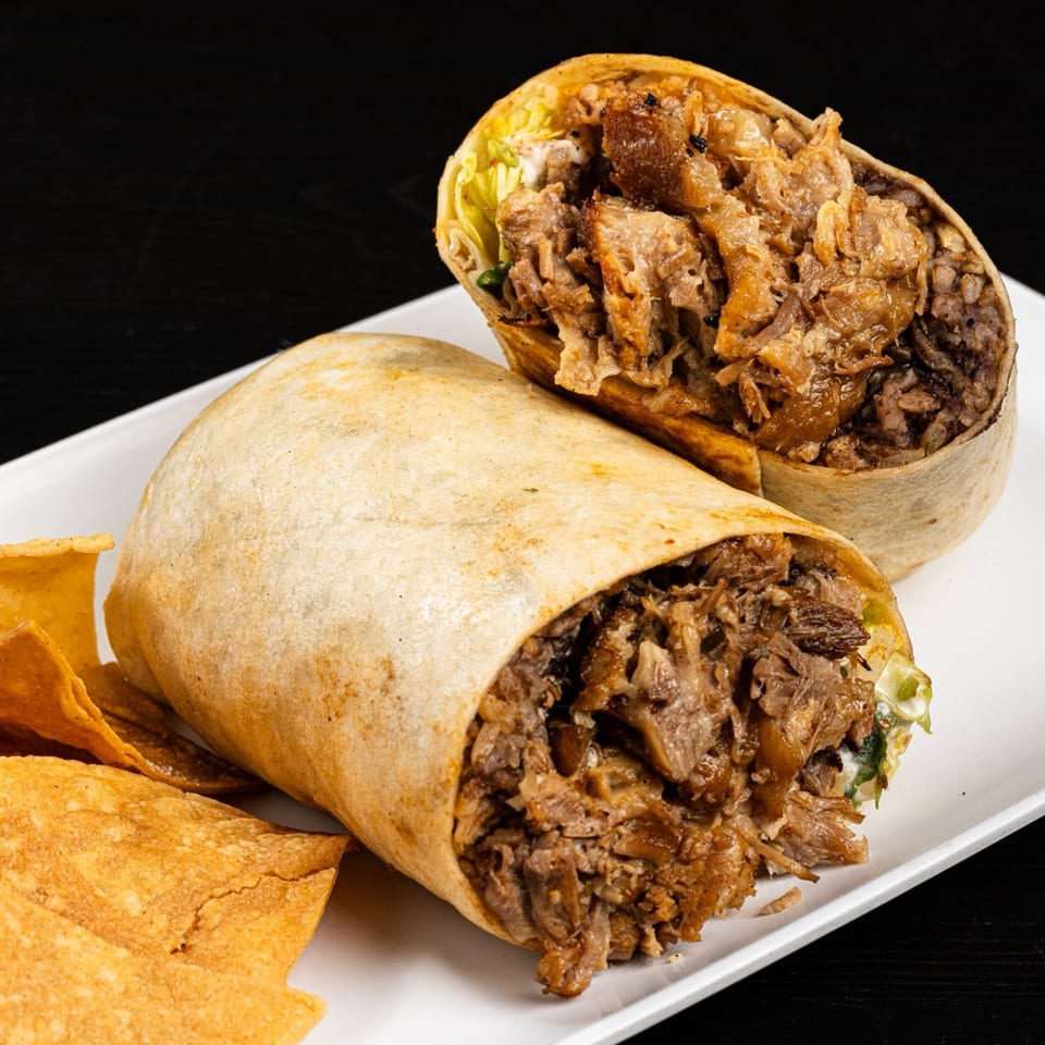 Two large, sliced Tex-Mex burritos filled with meat and rice, served with tortilla chips.